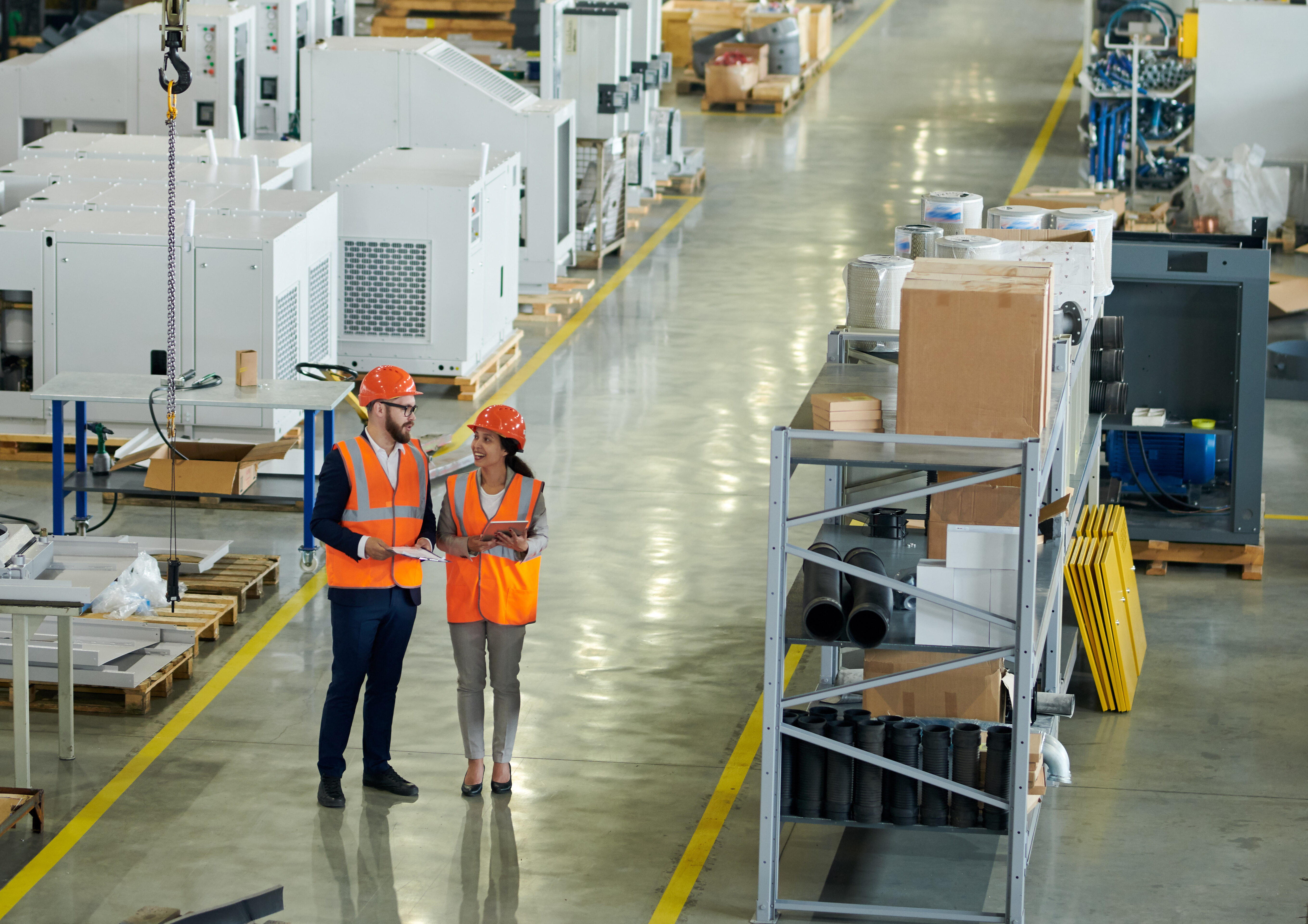 a man and woman in orange vests and helmets in a warehouse